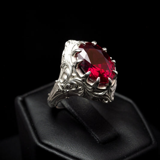 Silver ring with a red gemstone on a black background
