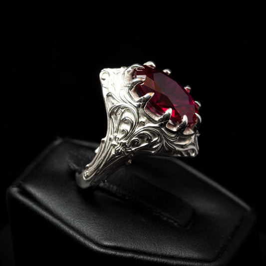 Silver ring with a red gemstone on a black background