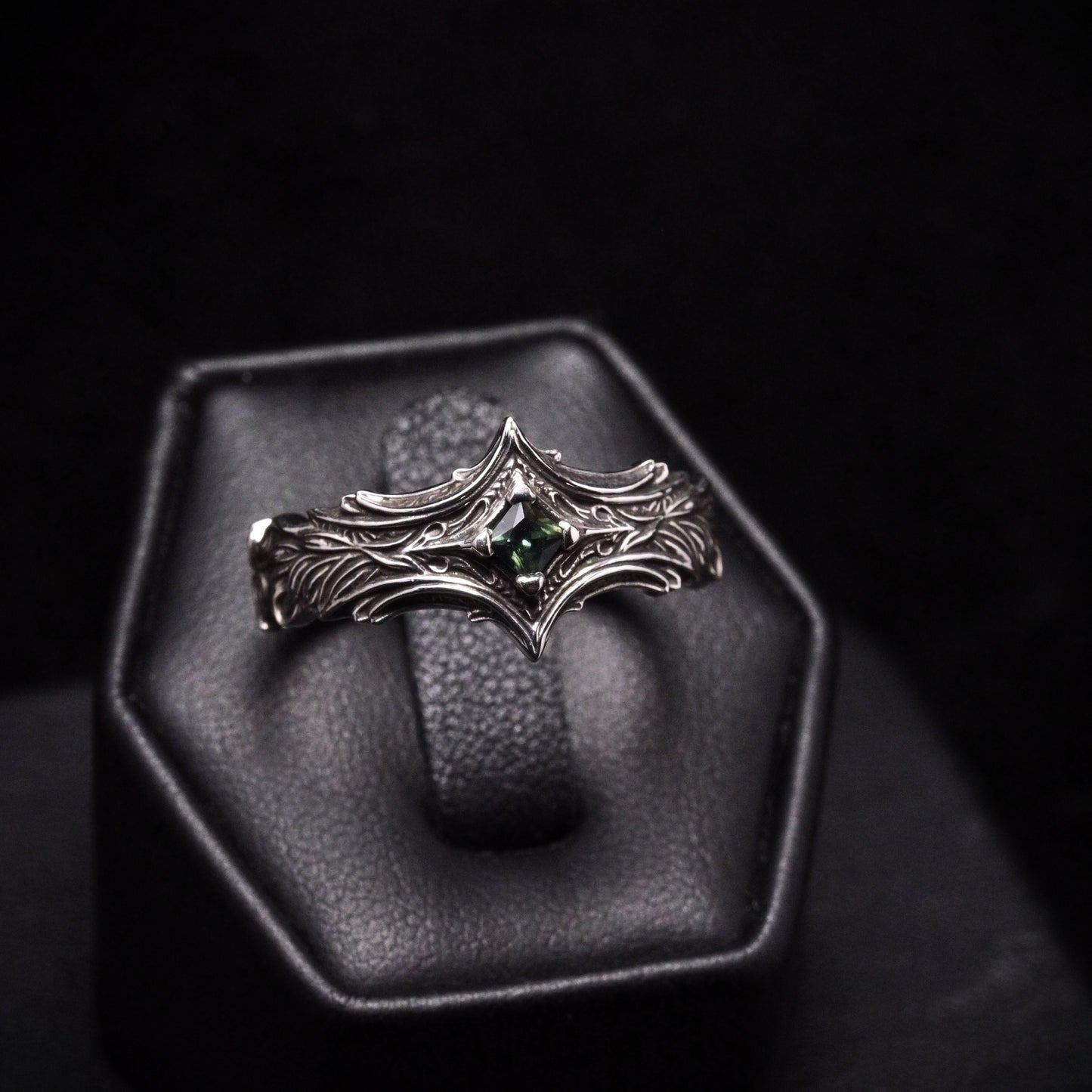 Silver ring with green gemstone on a dark background