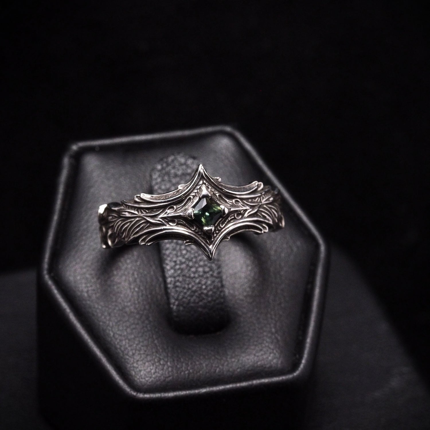 Silver ring with green gemstone on a dark background