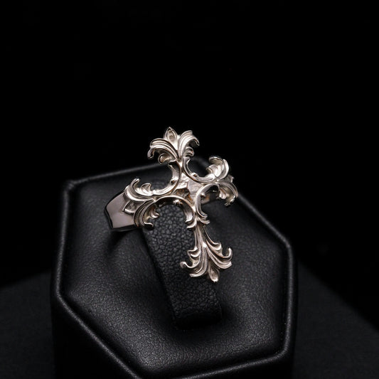 Decorative silver pendant on a black cushion against a dark background