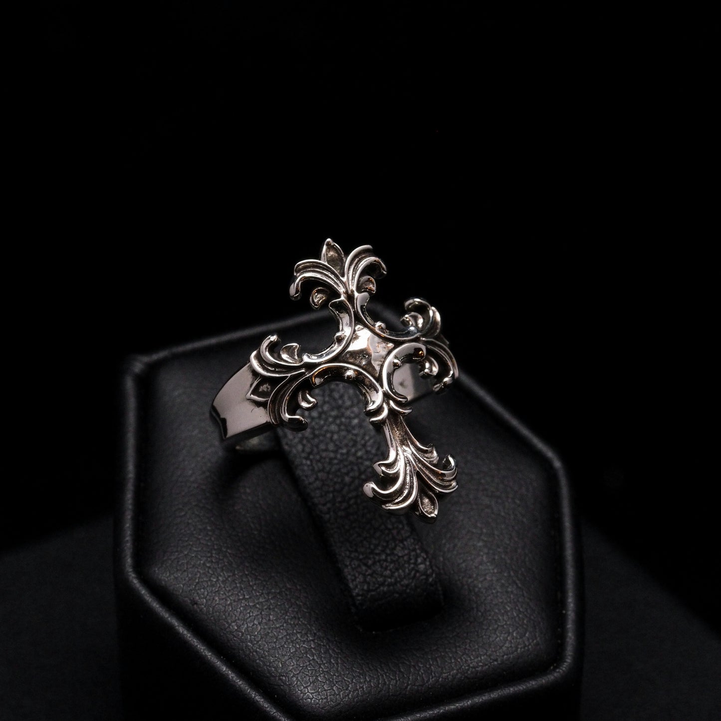 Silver cross pendant on a black leather strap in a hexagonal black box